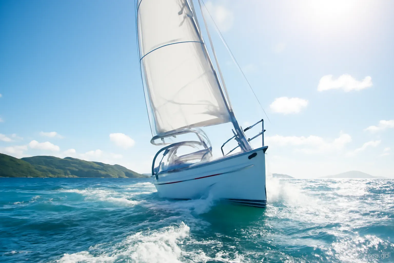Sloop heeling under reefed mainsail in strong trade wind off Grenada's south coast, whitecaps, low-angle shot from the water, bright morning sun