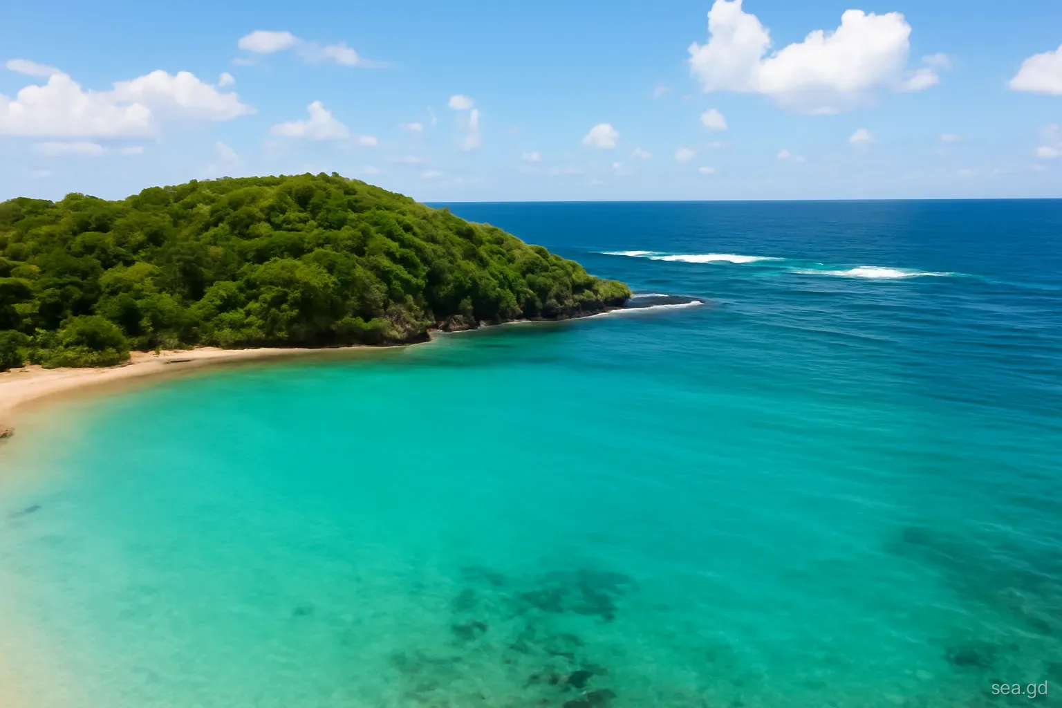 Calm glassy turquoise water in a sheltered west coast bay of Grenada contrasted with whitecaps on the open sea beyond the headland, aerial view, midday sun